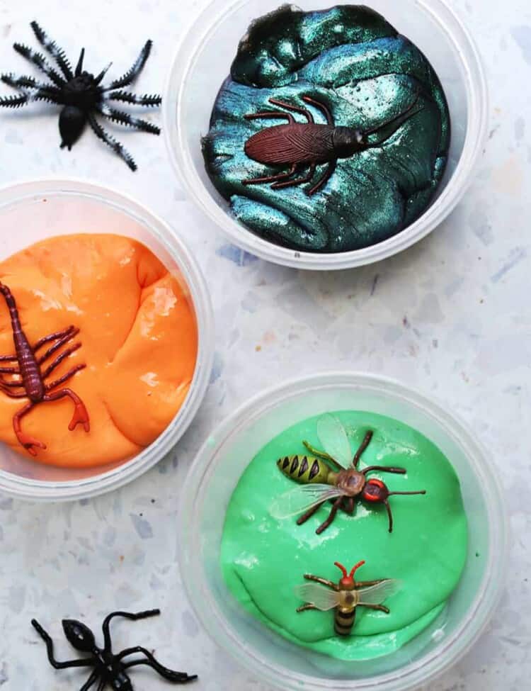 galaxy slime, orange and green slime on a counter with fake bugs.