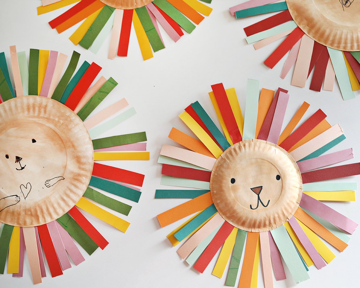 strips of paper in various colors and paper plates painted as lion faces to create paper plate lions. 