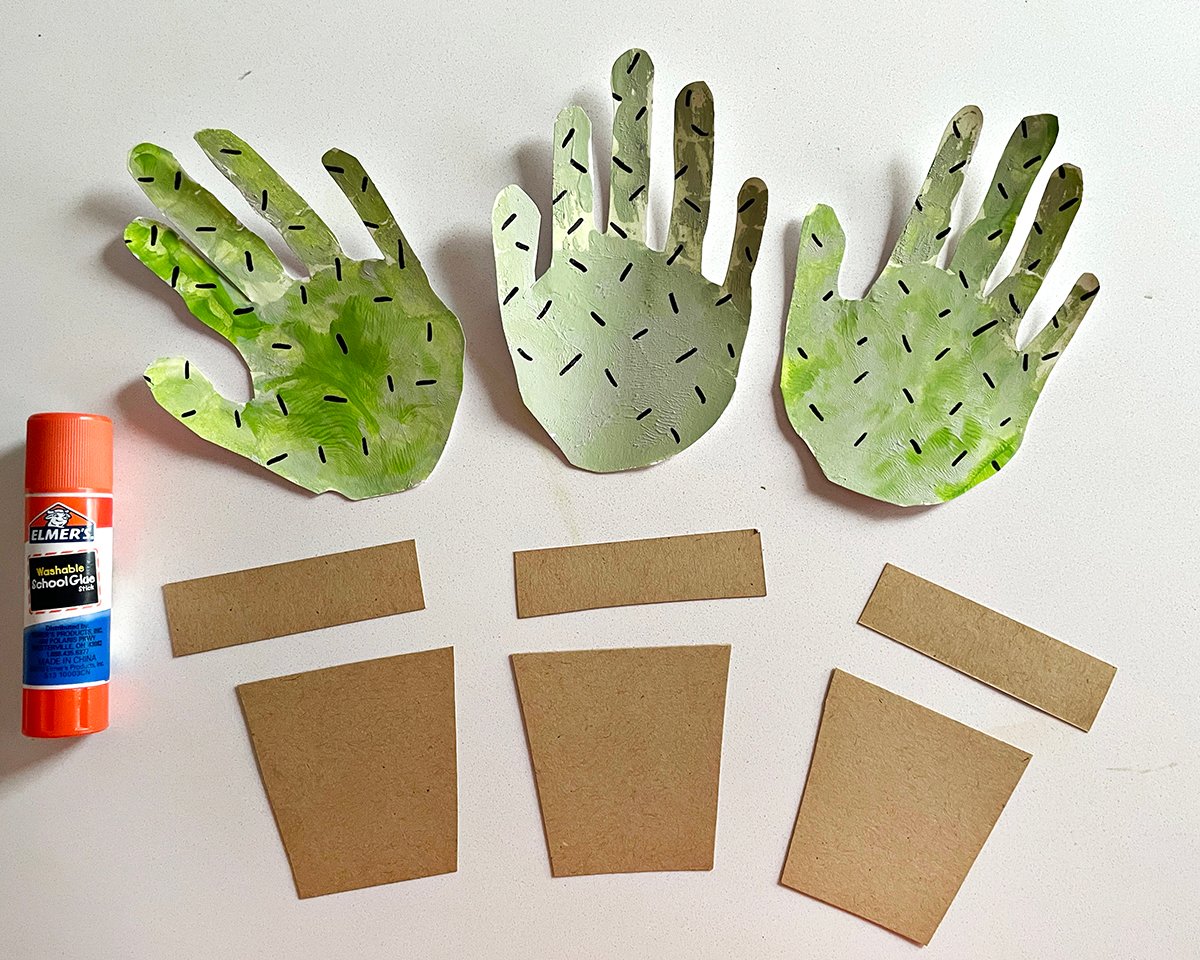 glue stick, paper handprints painted green and brown kraft paper. 