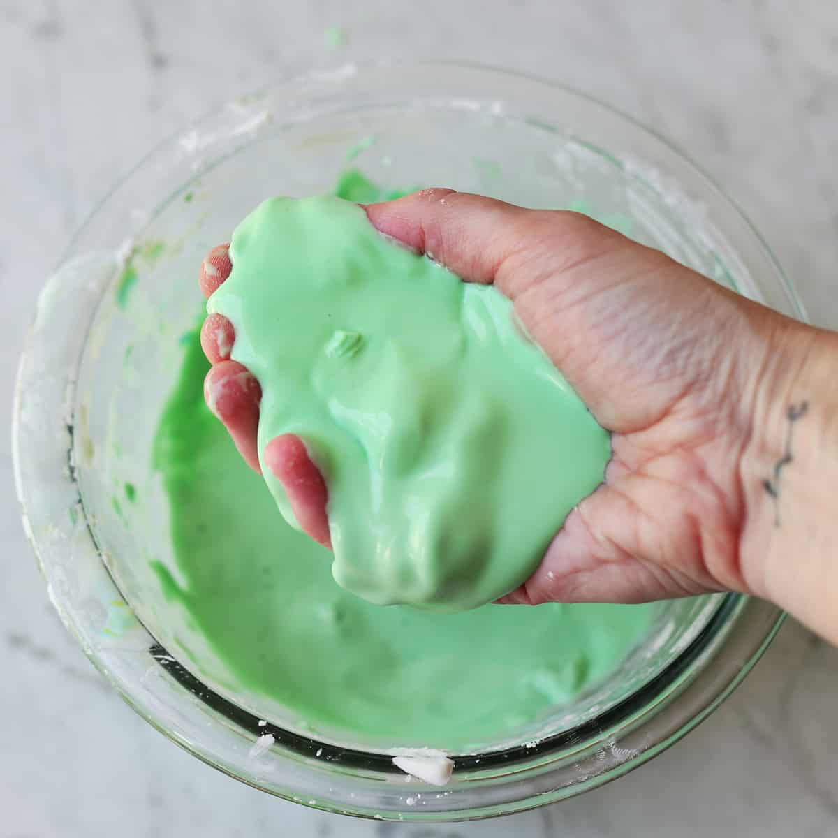 Hand holding green oobleck goop mixture. 