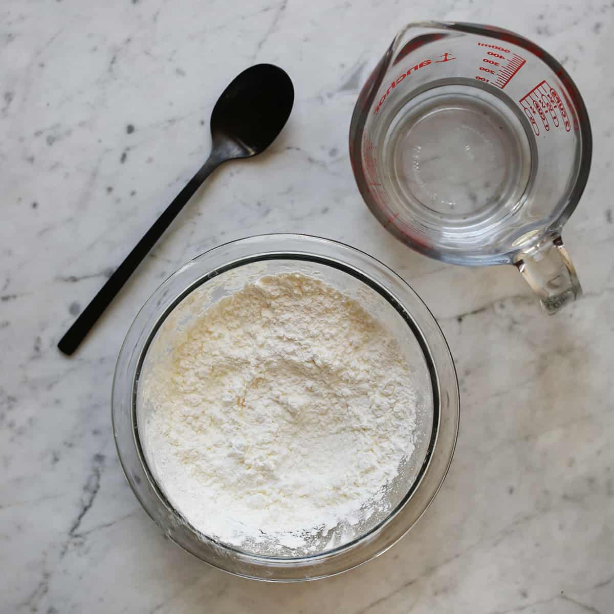 bowl of cornstarch, water and a spoon sitting on a counter. 