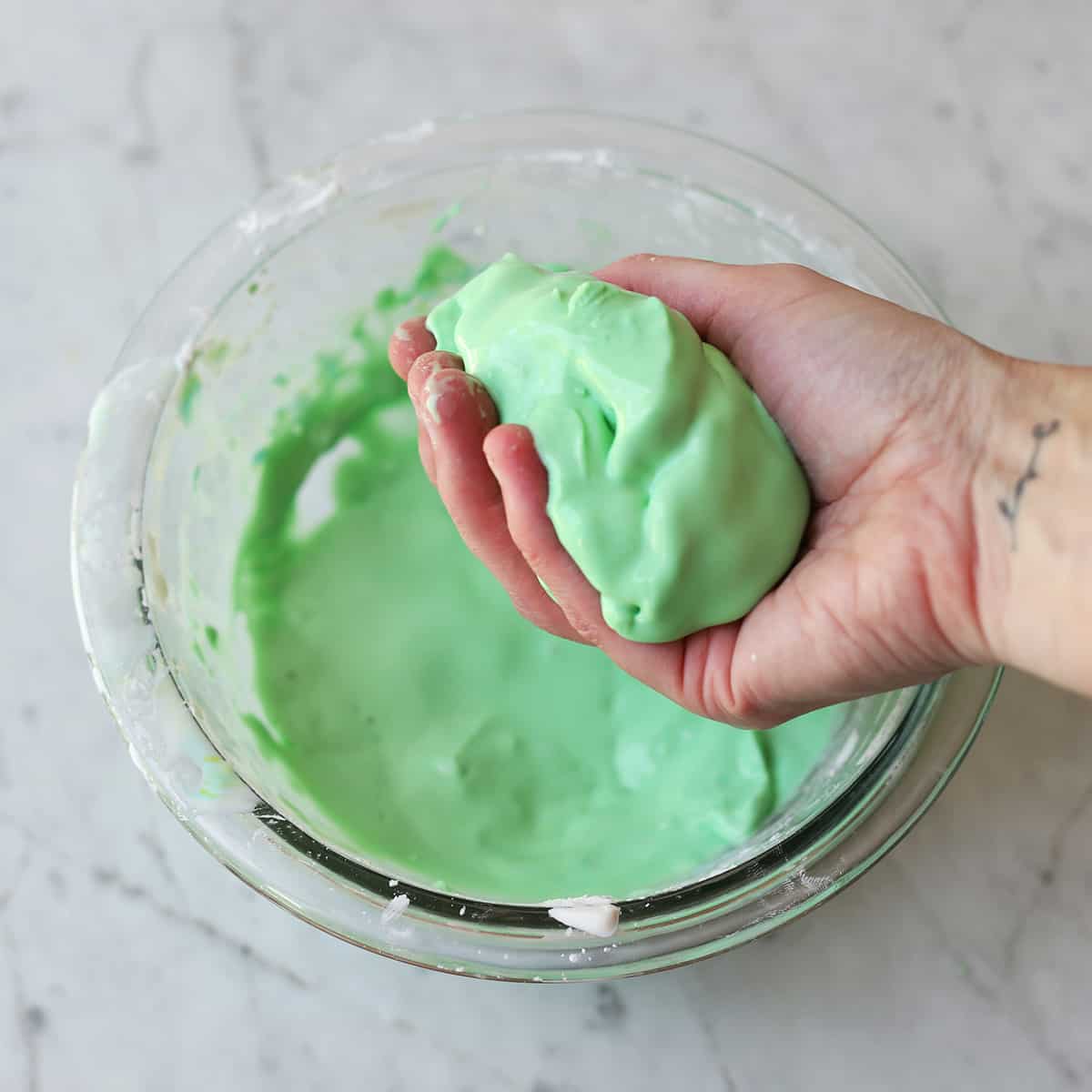 hand holding oobleck over a bowl. 