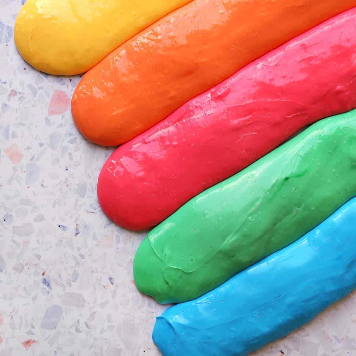 Yellow, orange, red, green and blue slime on a counter. 