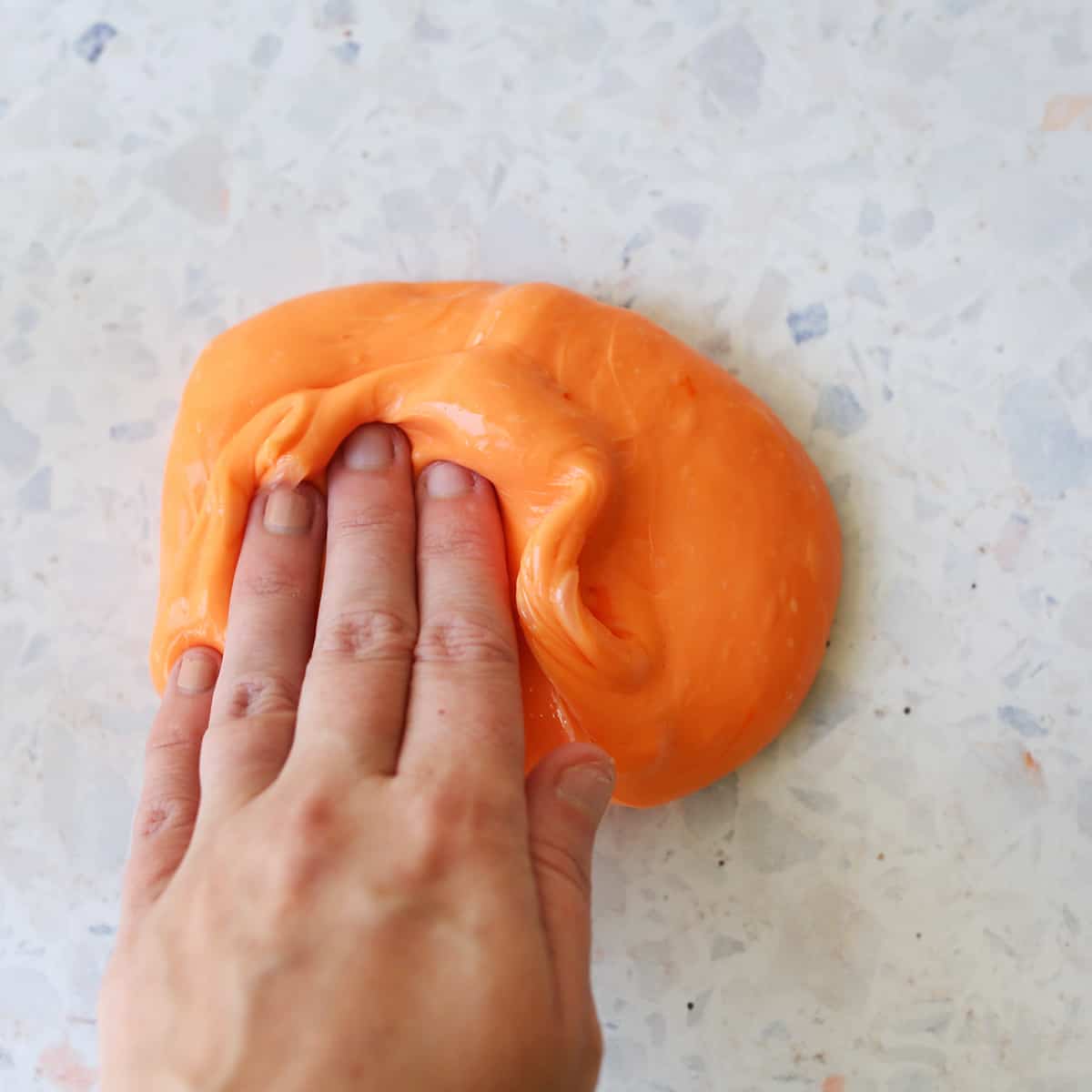 Hand kneading orange slime. 