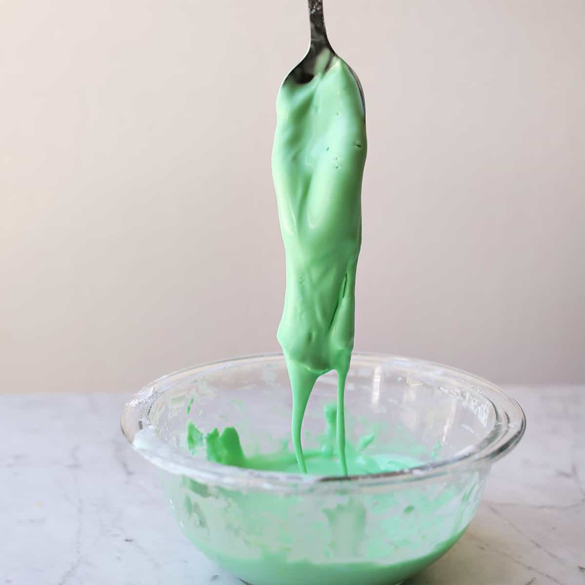 Green oobleck dripping into bowl. 