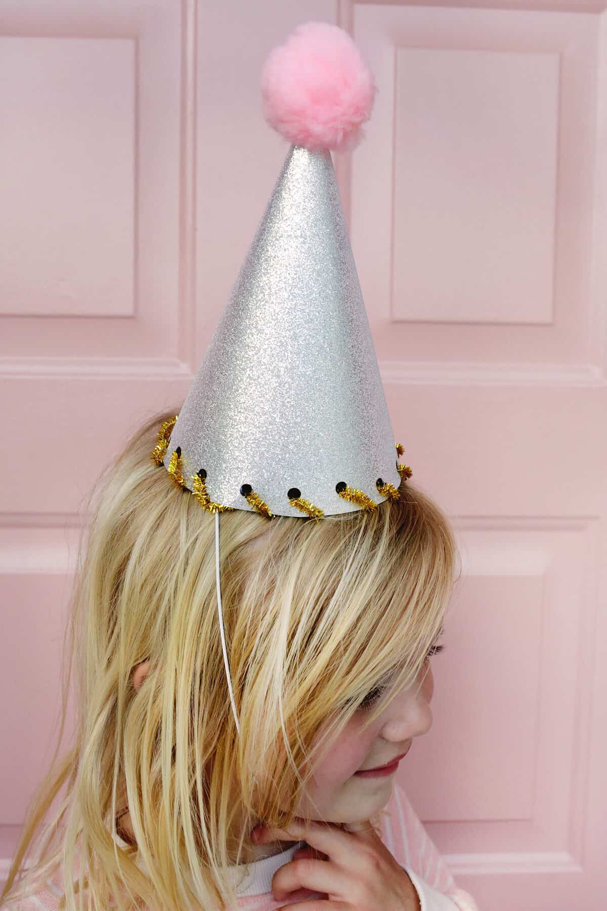 girl wearing silver party hat with pom pom