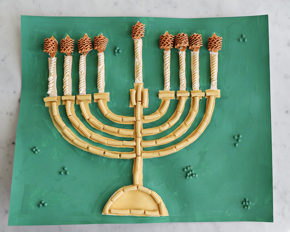 Paper painted green with noodles glued onto it to make a menorah. 