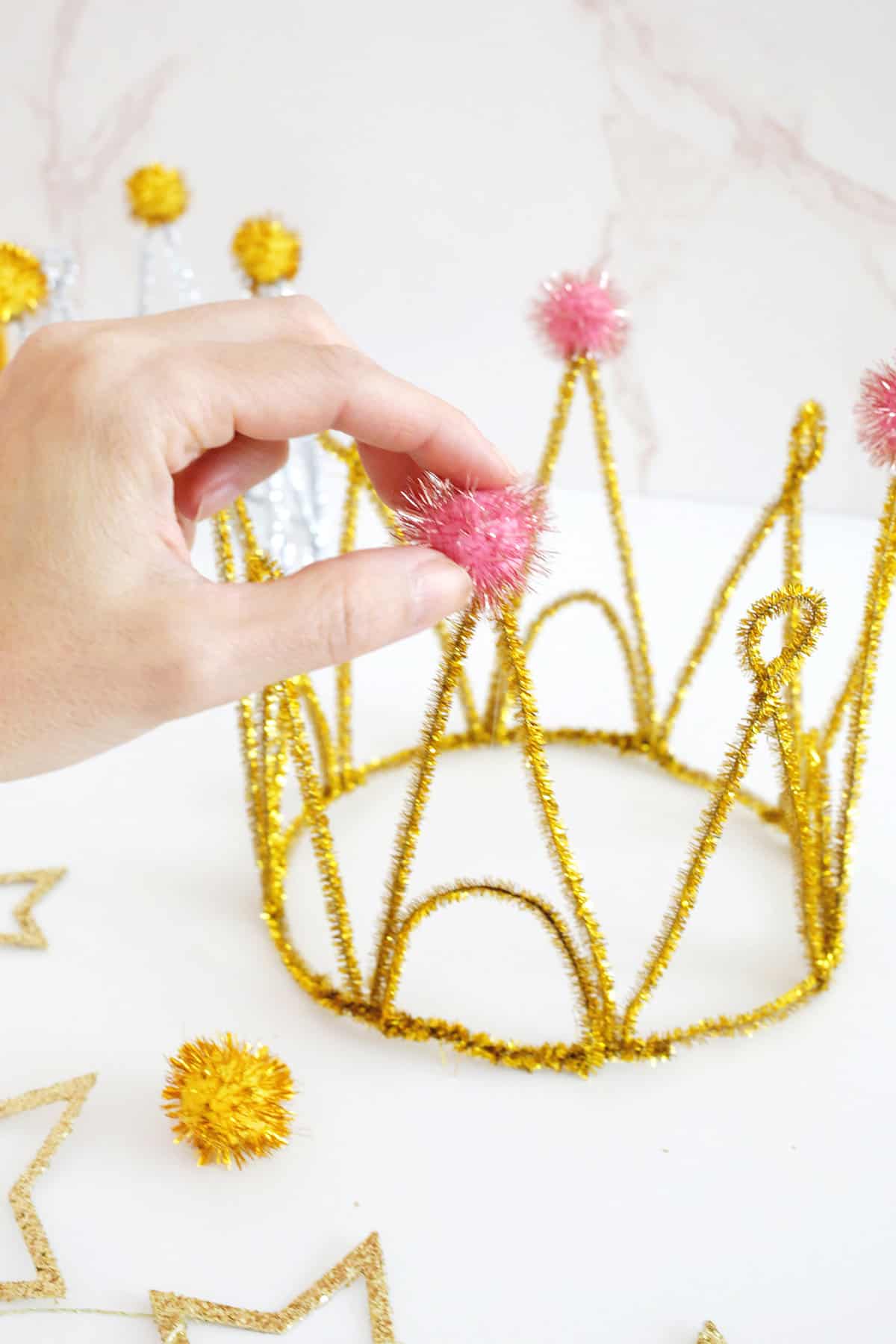 adding pom poms to pipe cleaner crown