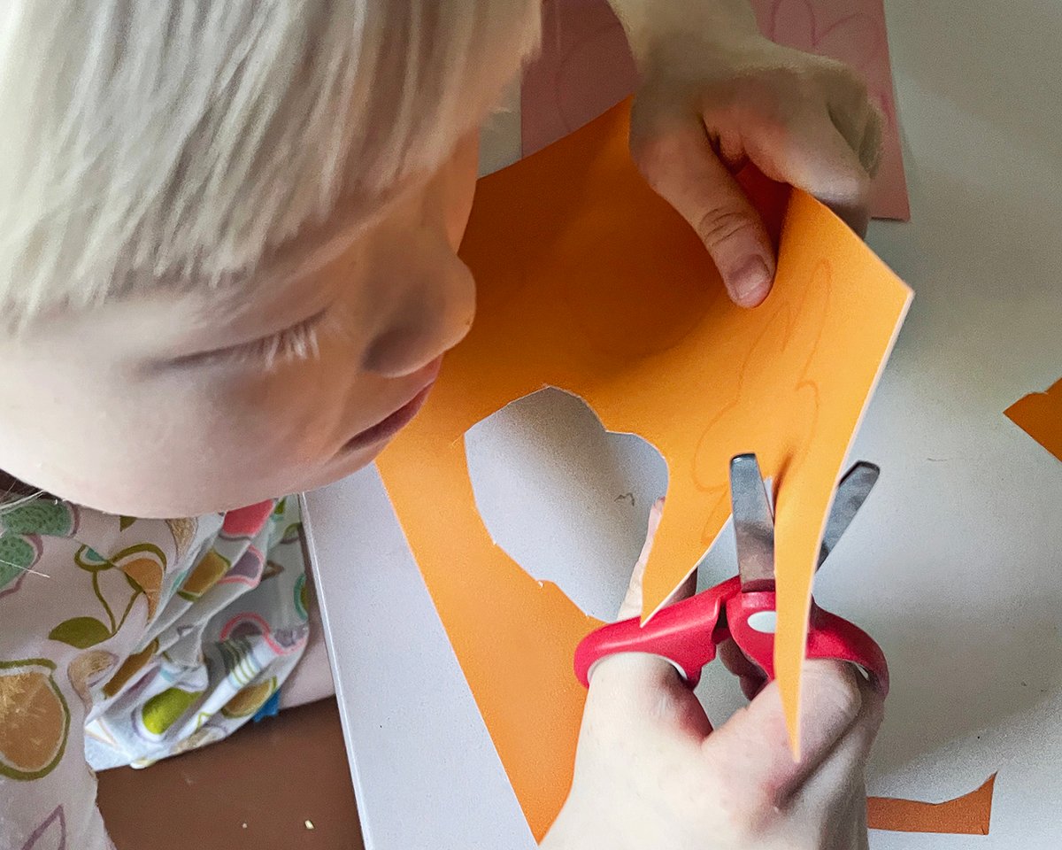 child cutting paper with kid-friendly scissors. 