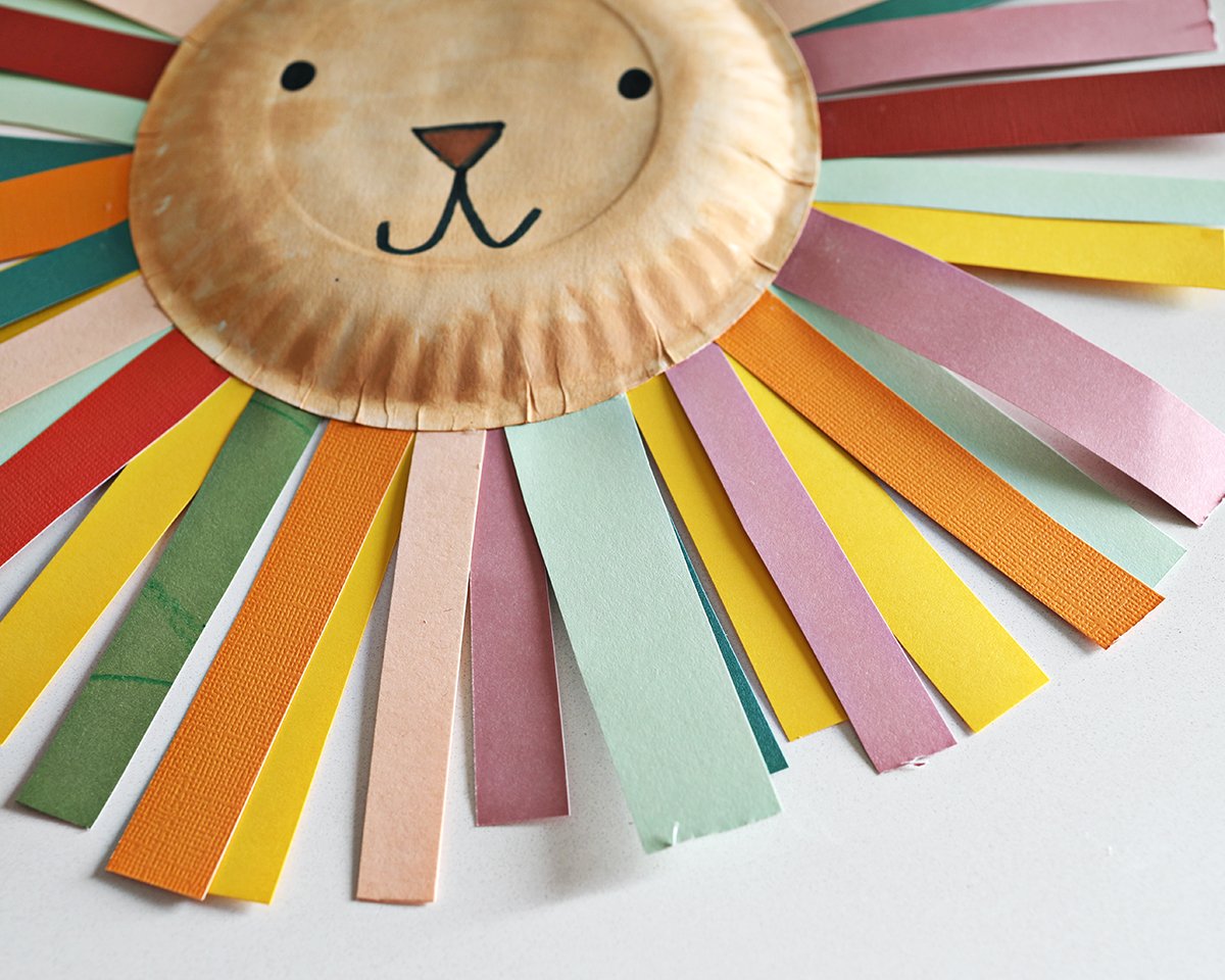 paper plate decorated as a lion with rainbow strips of paper as a mane. 