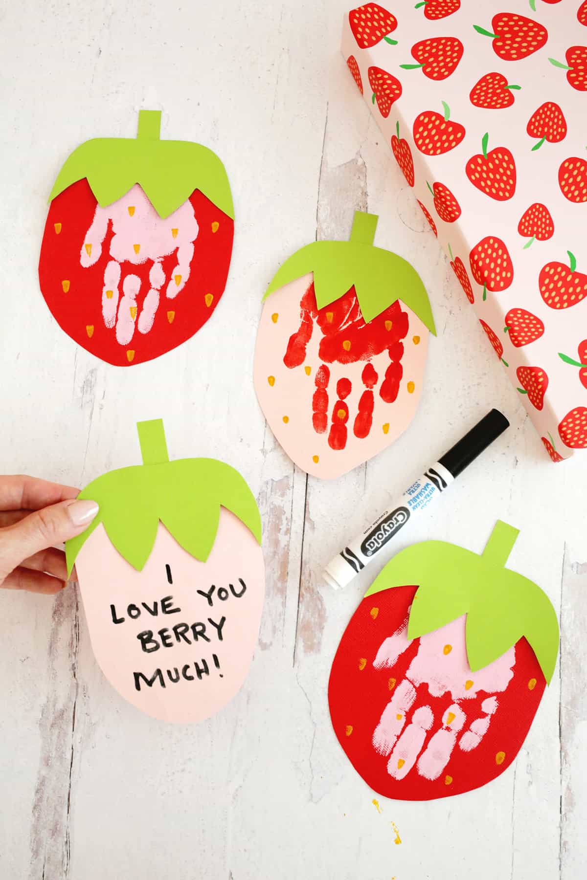 strawberry handprint cards sitting on table