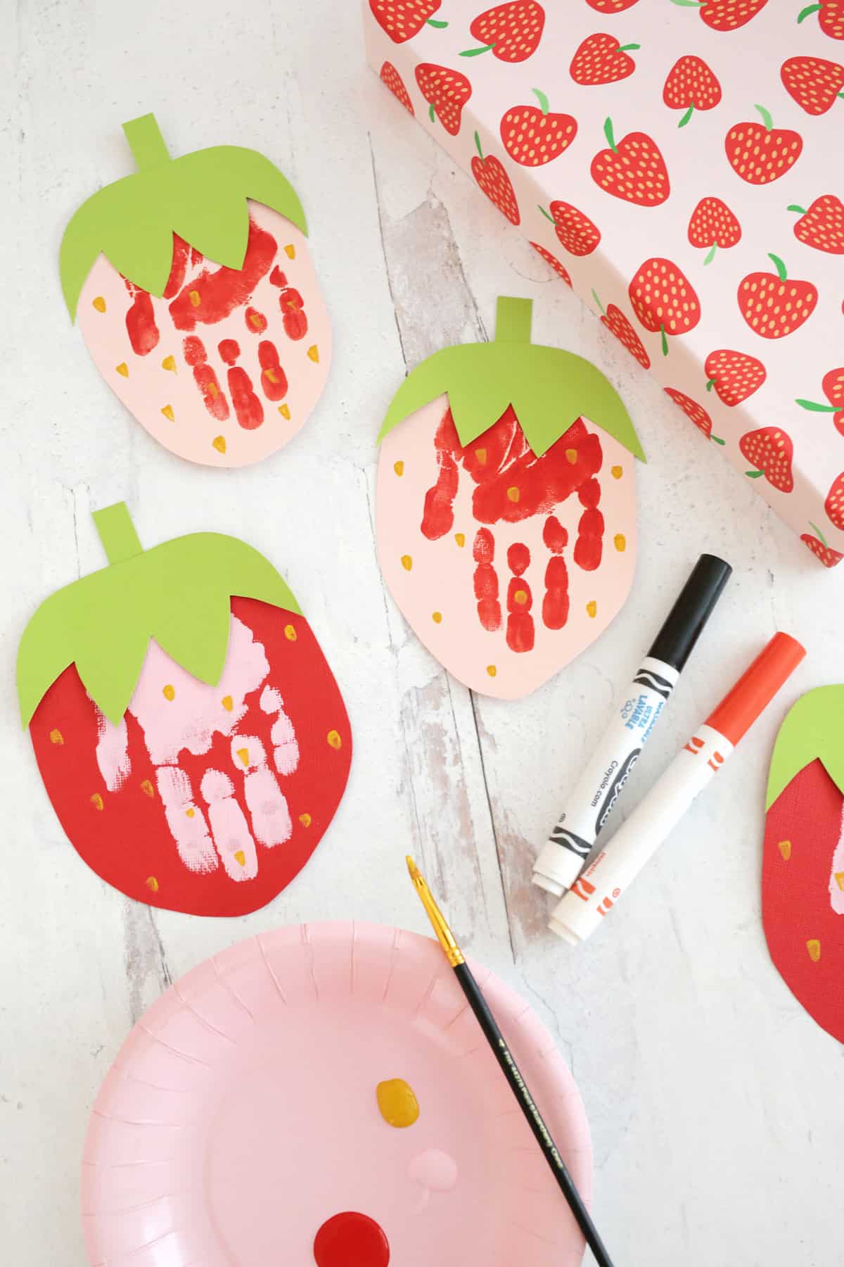 strawberry handprint cards sitting on table