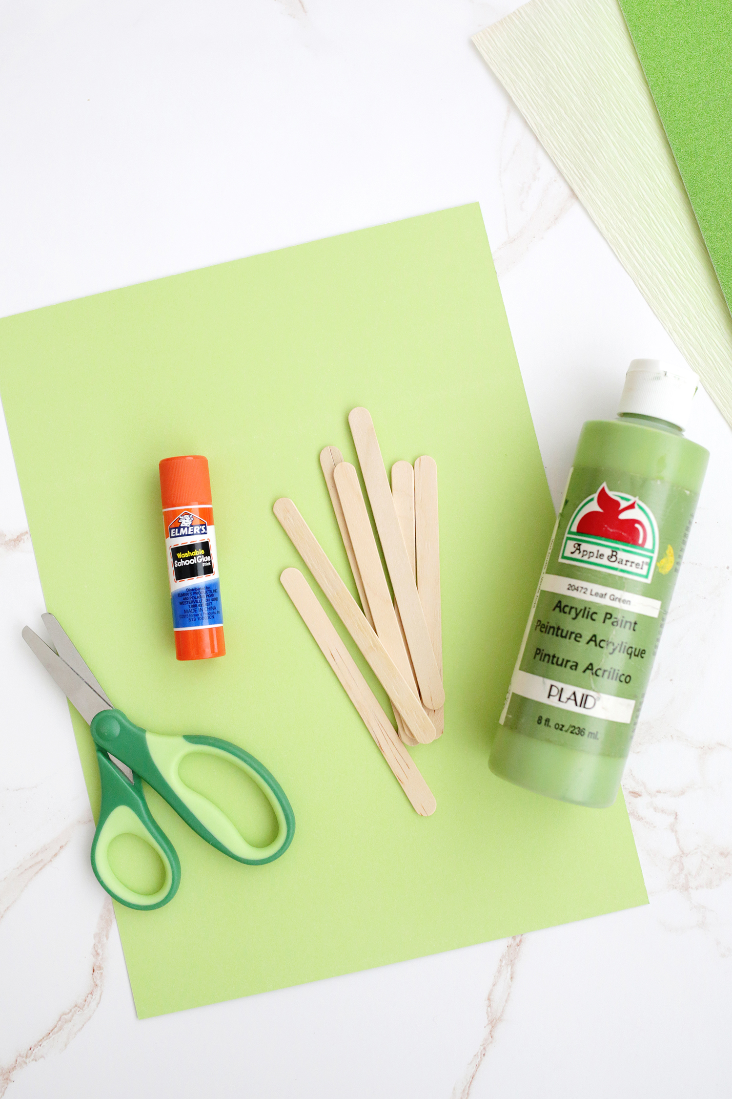 green paper, scissors, popsicle stick, paint, and glue stick