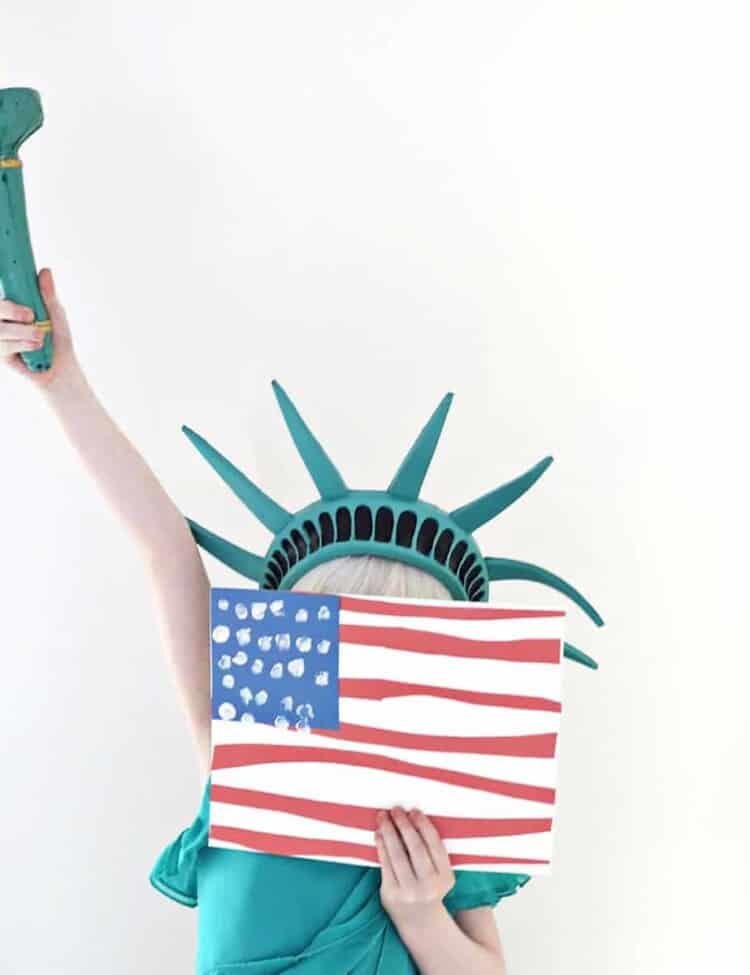 child dressed as the statue of liberty and holding fingerprint flag craft.