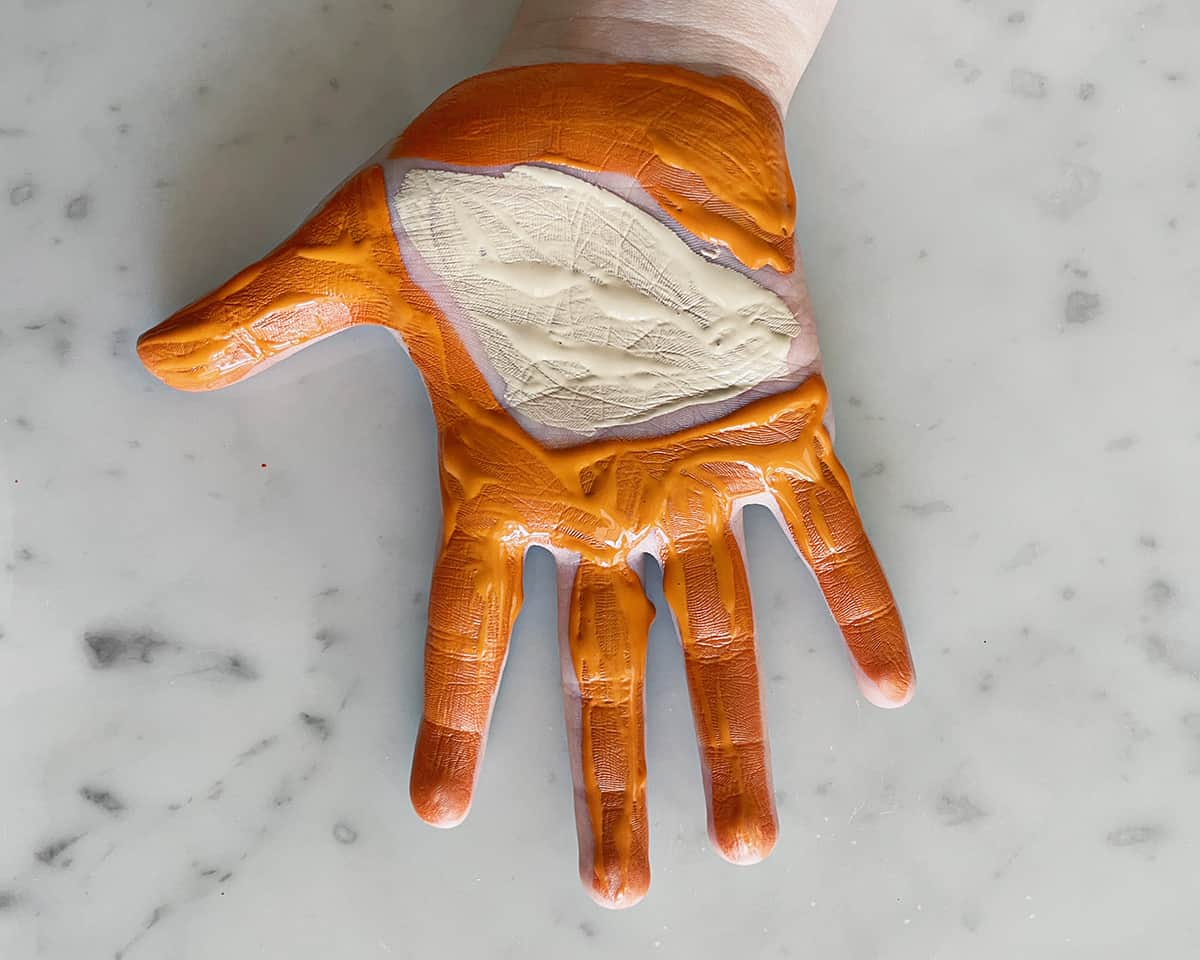 Child's handprint covered in beige and orange paint. 