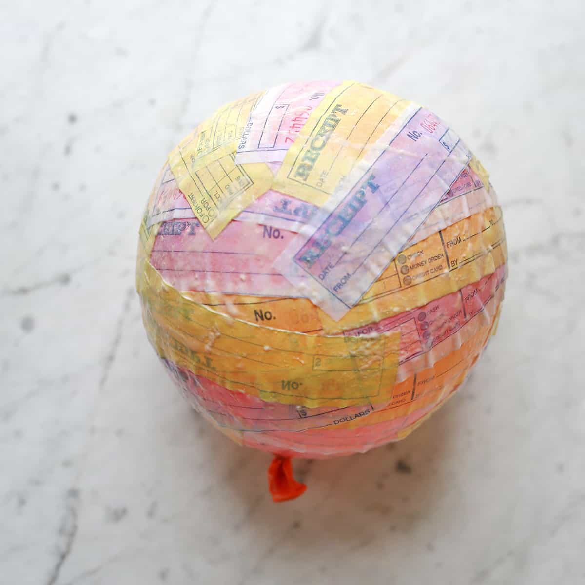 Balloon covered with paper pieces dipped in paper-mache paste. 