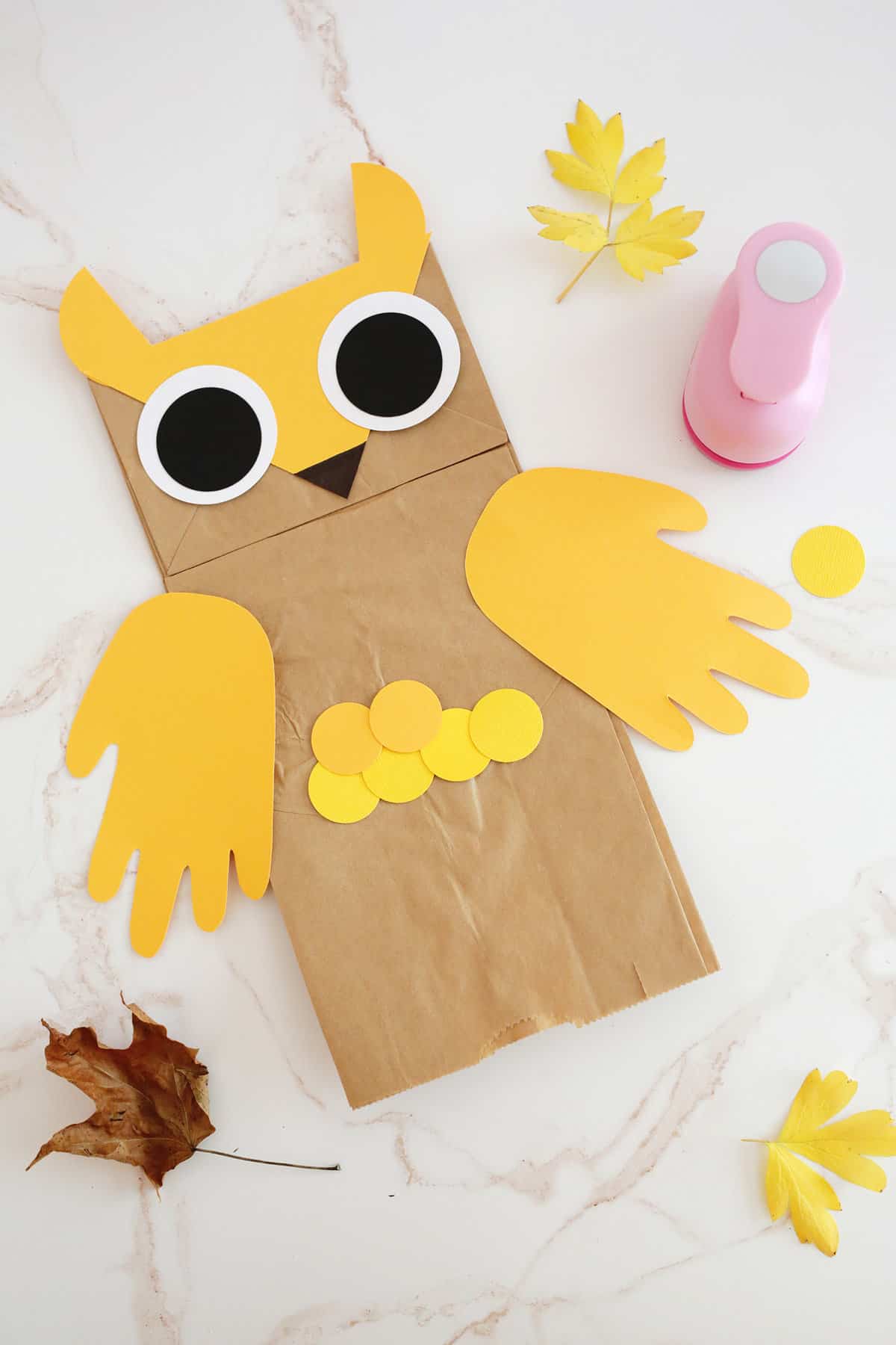 using paper circles to make feathers on a paper bag owl puppet