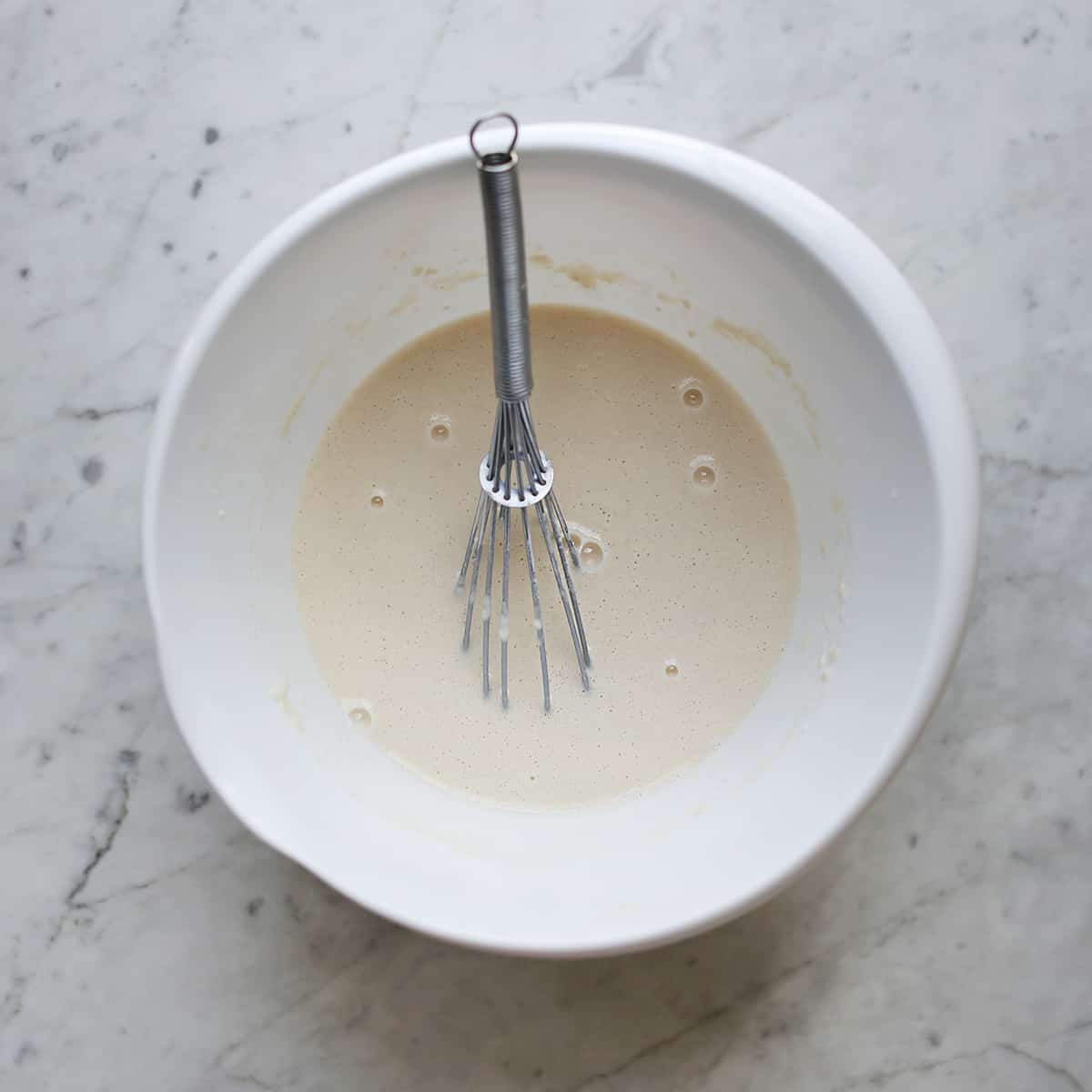 flour and water combined in a bowl with a whisk. 