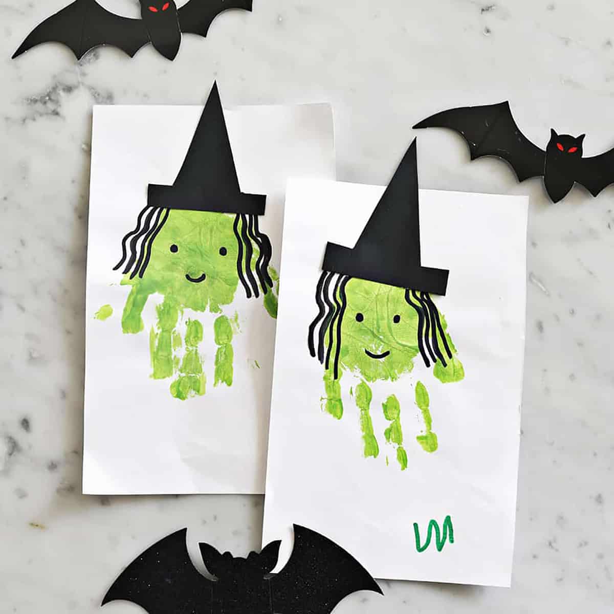 two pieces of construction paper with green handprints to look like witches.