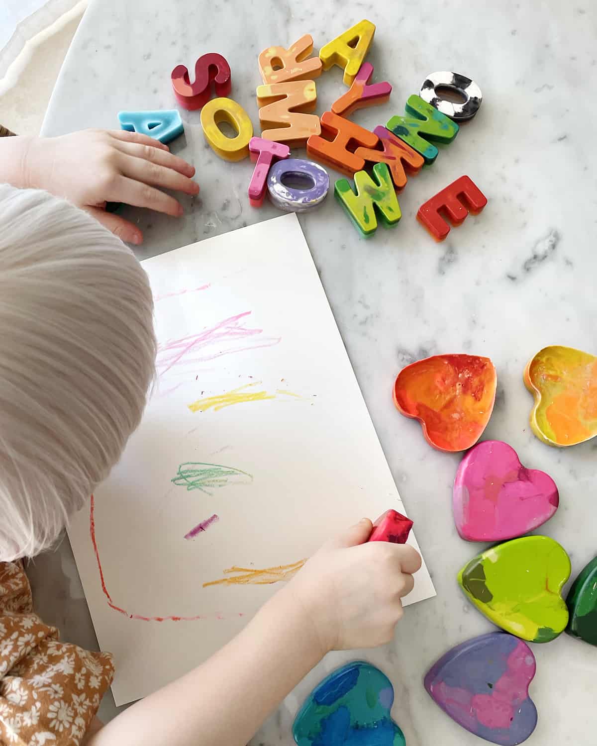 child coloring with heart-shaped crayon. 
