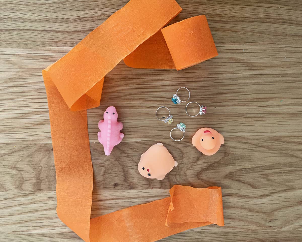 prizes and toys sitting next to roll of orange crepe paper.