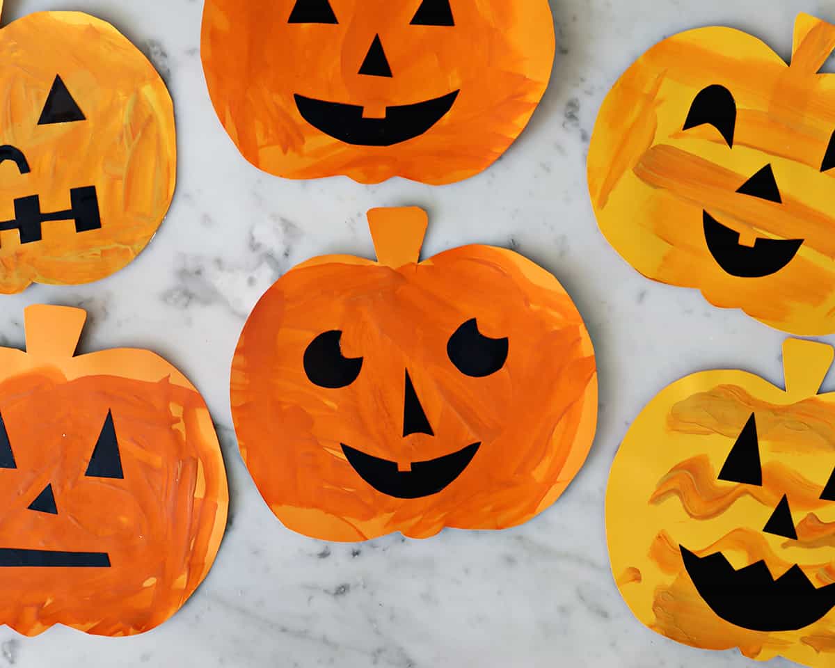 Paper cut out pumpkins decorated with fun faces for Halloween.