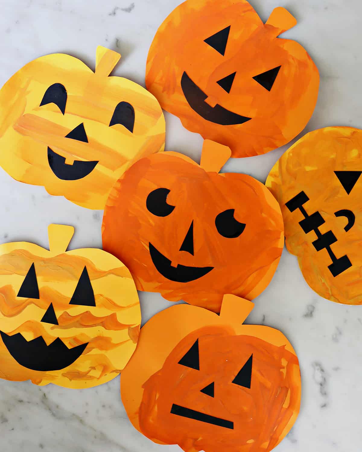 Jack-o-lantern craft for kids with cut out paper, faces, and paint.