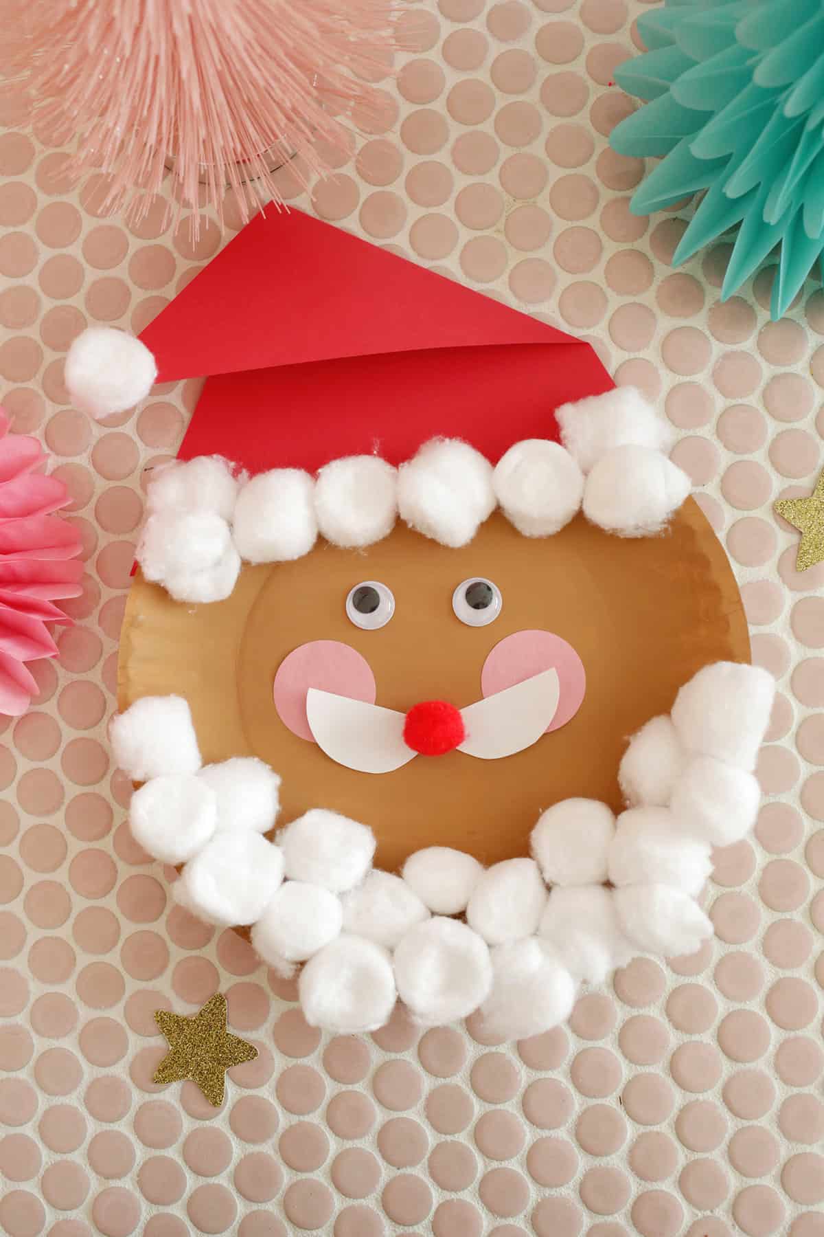 adding cotton balls to a paper plate santa for beard and hat
