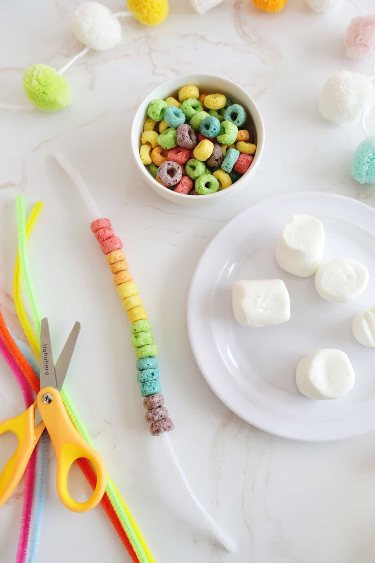 threading fruit loops onto a pipe cleaner in rainbow order