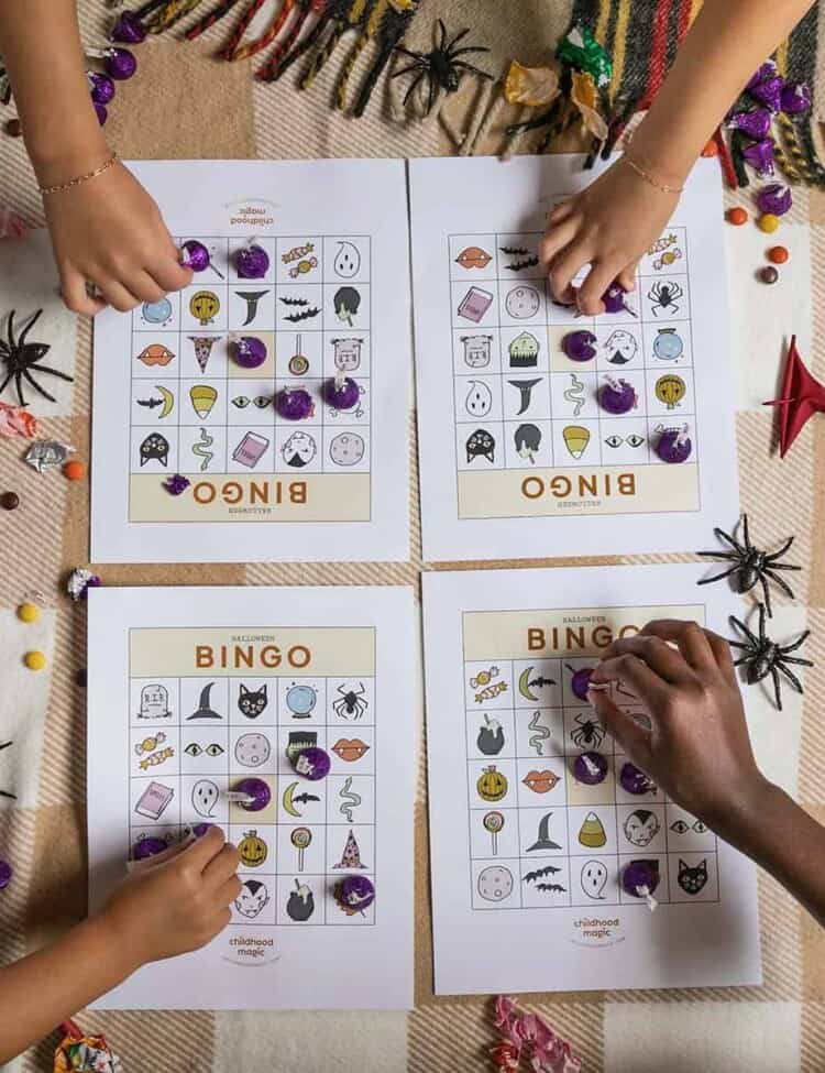 children's hands placing tokens on Halloween-themed Bingo cards.