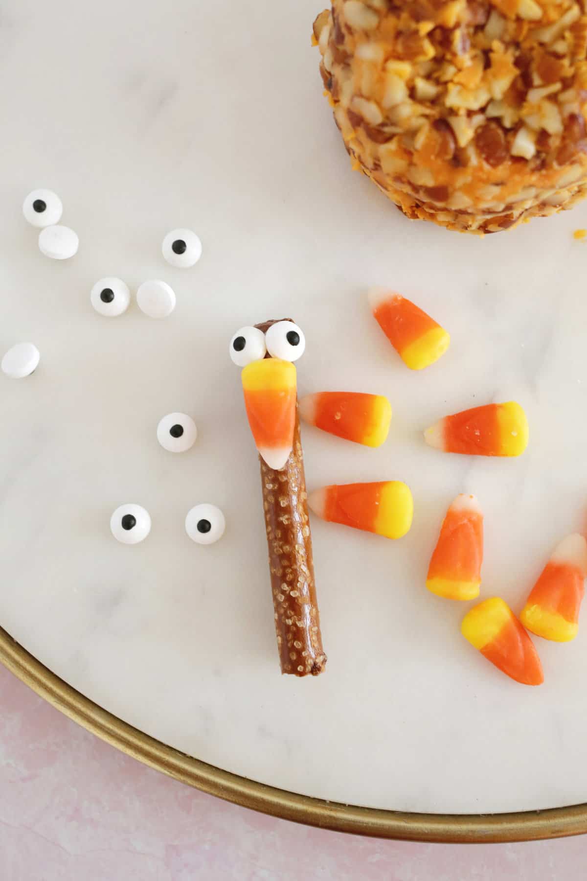 candy eyes, pretzel rod, and candy corn to make a turkey face for turkey cheeseball