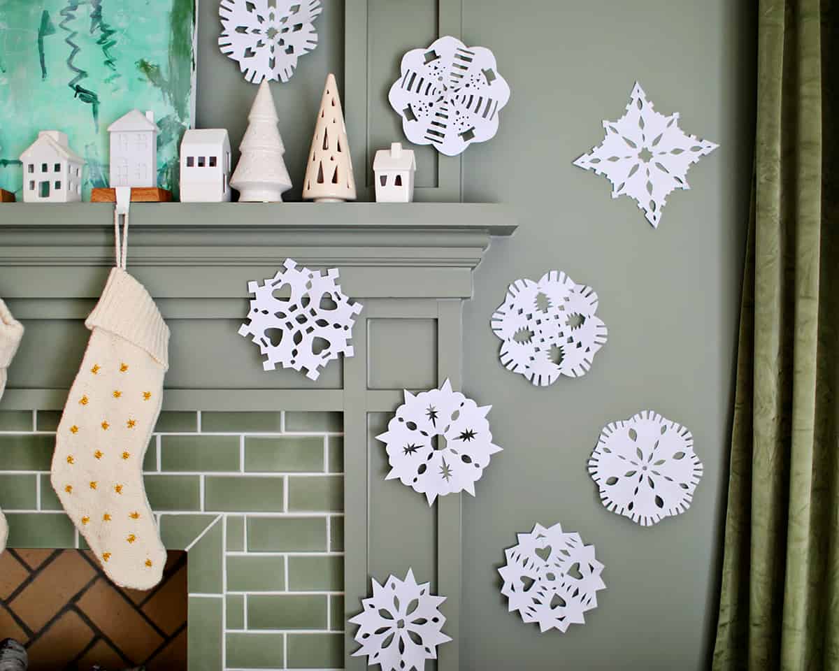 Stockings hanging on a fireplace and paper snowflakes taped to the wall. 