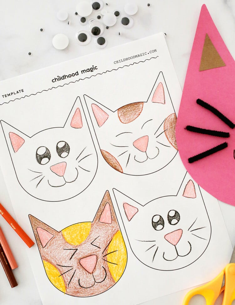 Coloring page with cat faces next to a cut out cat made from pink paper and with pipe cleaners.