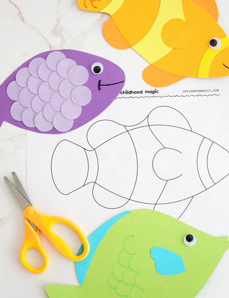 yellow, purple and green fish shapes cut out of construction paper on top of an outline of a fish on a white background.