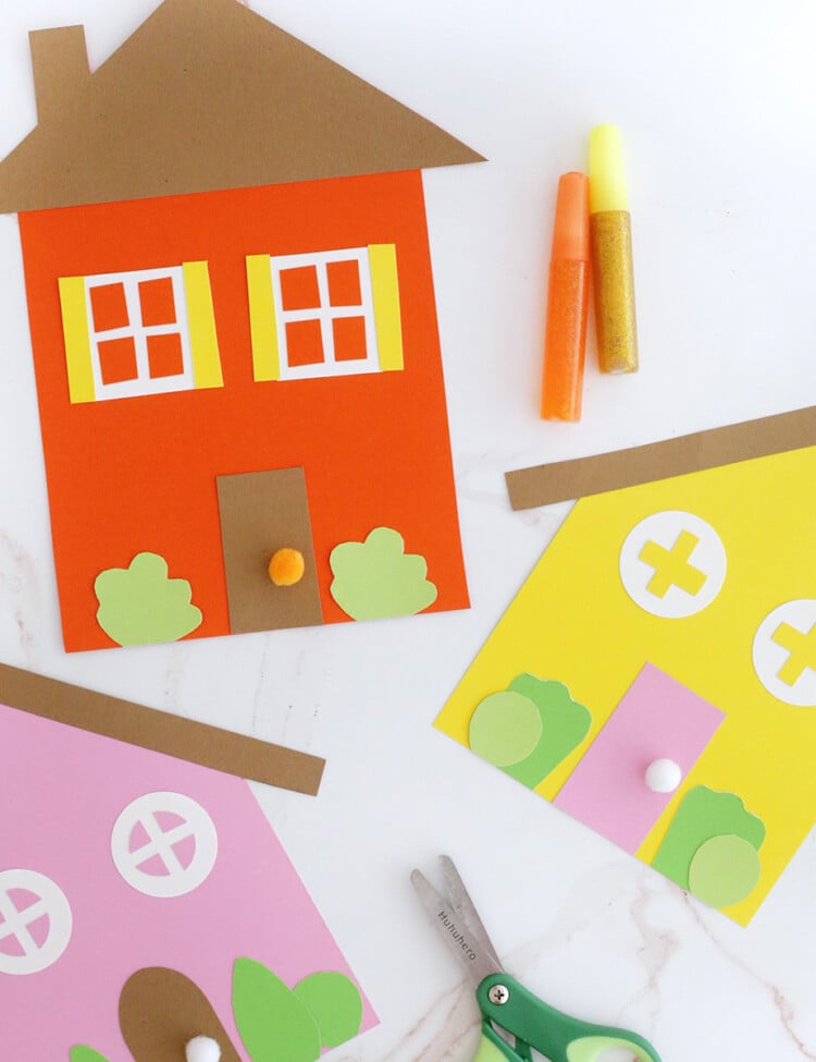 houses cut out of paper and decorated. Green kids scissors.