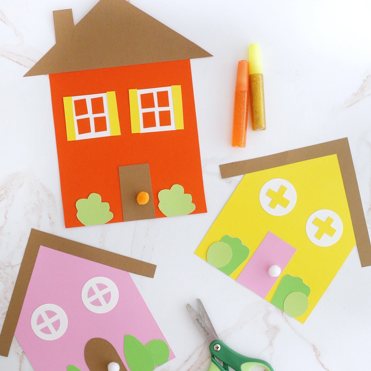 houses cut out of paper and decorated. Green kids scissors.