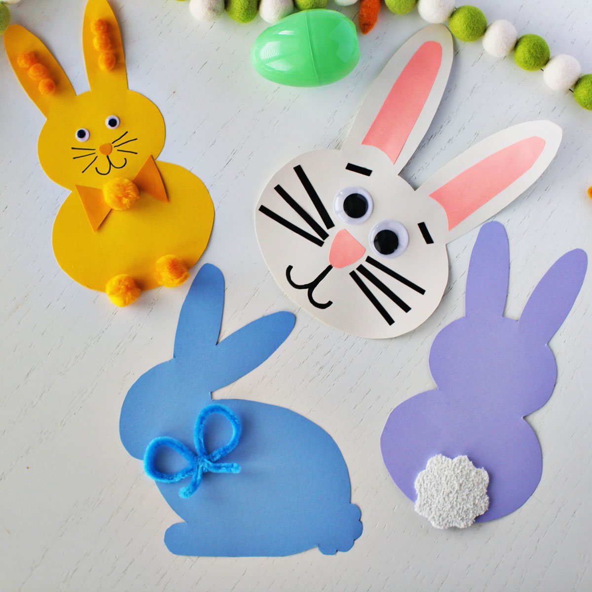 Bunny shapes cut out of cardstock and decorated with pipe cleaners, pom poms and googley eyes. 