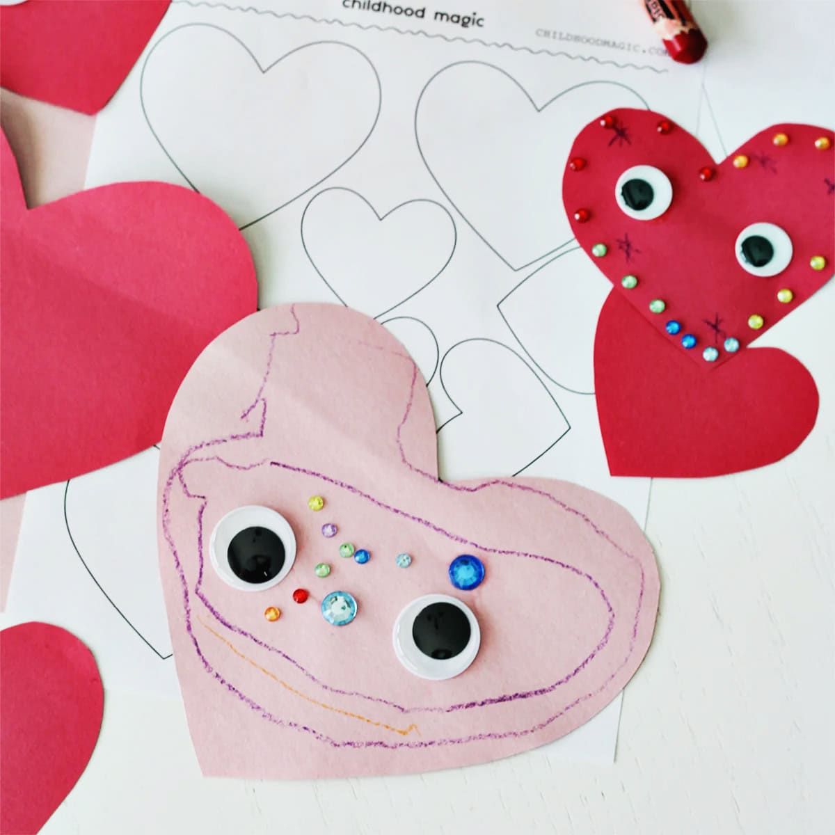 pink construction paper cut into a heart shape and decorated with stickers, googley eyes and crayons.