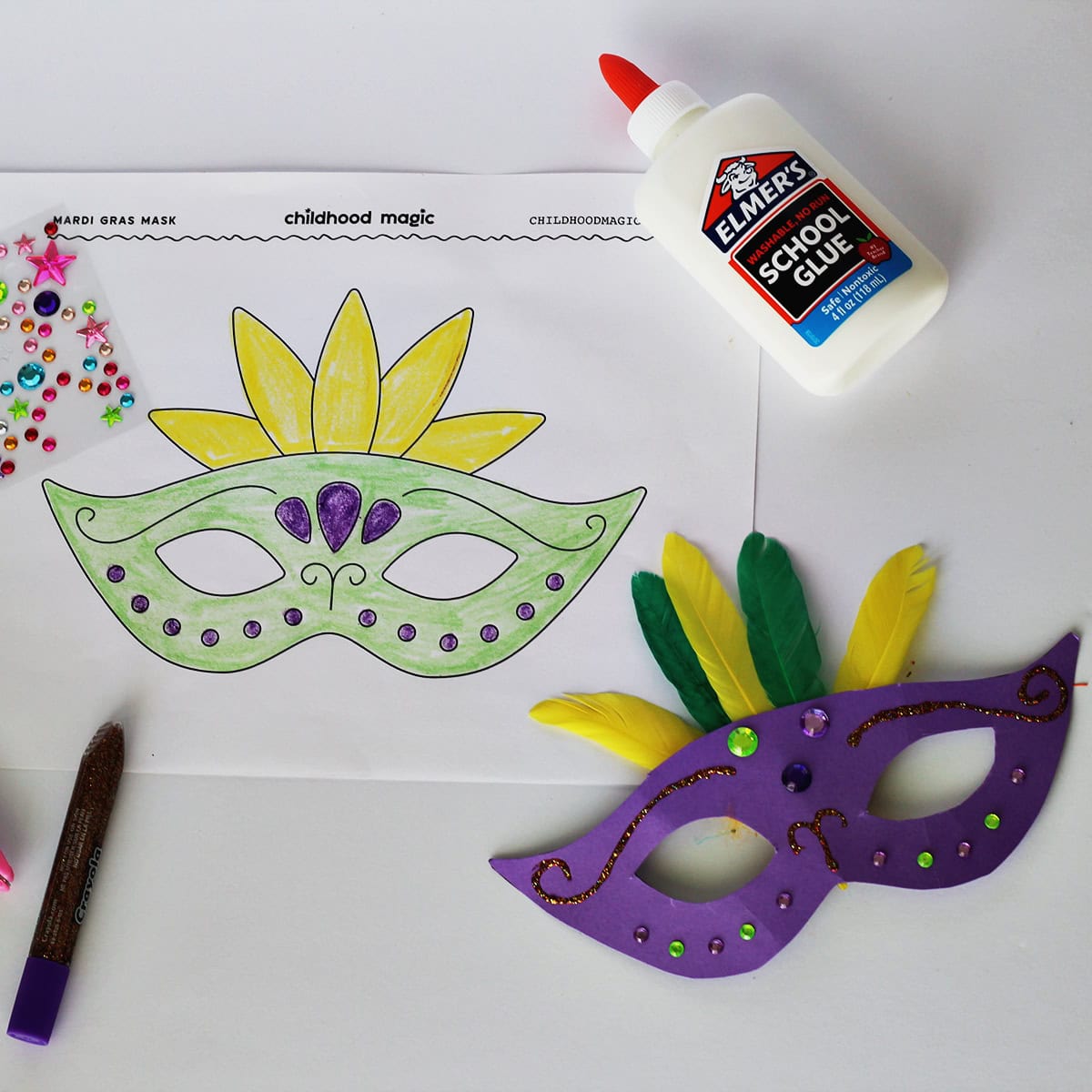 Mask made out of purple cardstock, green and yellow featuers and jewel stickers next to a coloring page with the same mask on it. Next to the paper is a bottle of glue.
