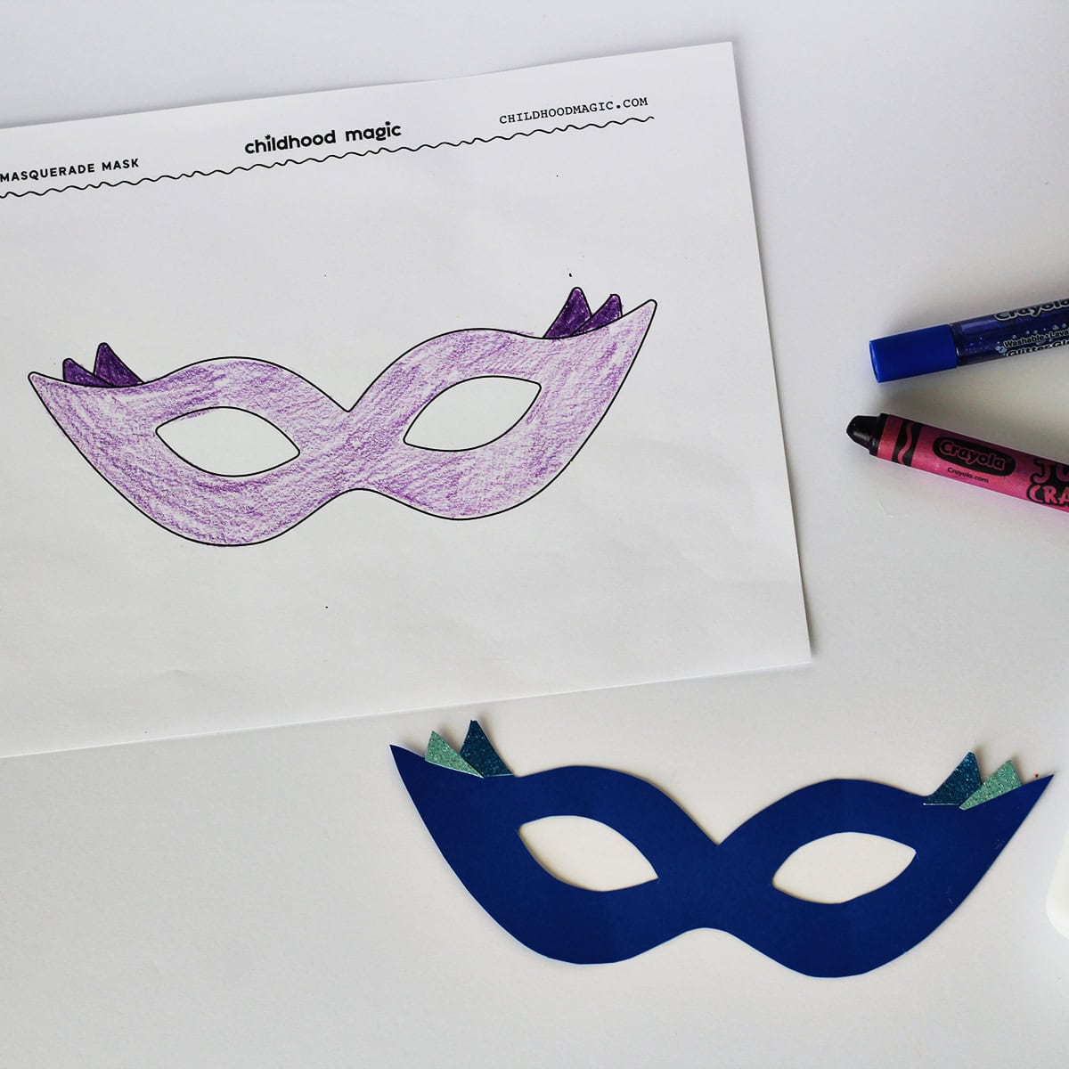 Mask made out of bluecardstock next to a coloring page with the same mask on it. Next to the paper is a purple crayon. 