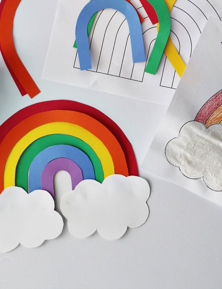 cardstock cut and glued together to make a rainbow next to a rainbow coloring page and a bottle of glue on a white table.