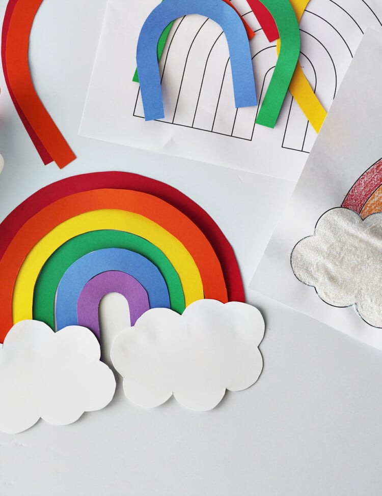 cardstock cut and glued together to make a rainbow next to a rainbow coloring page and a bottle of glue on a white table.