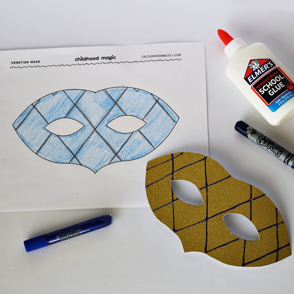Mask made out of gold glitter cardstock next to a coloring page with the same mask on it. Next to the paper is a bottle of glue and a blue glitter pen and a blue crayon. 