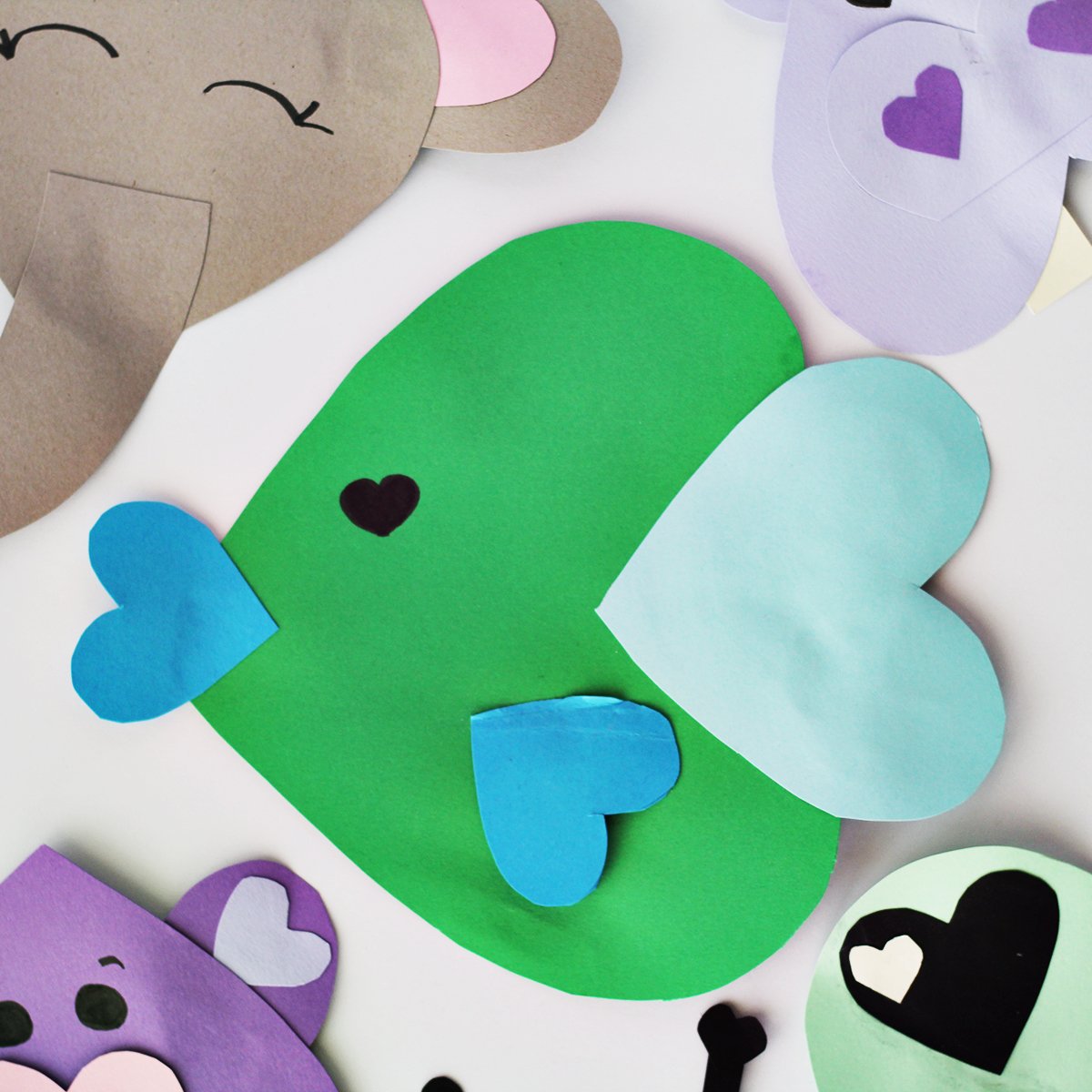 Green and blue cardstock paper cut into hearts and glued together to make a fish face. 