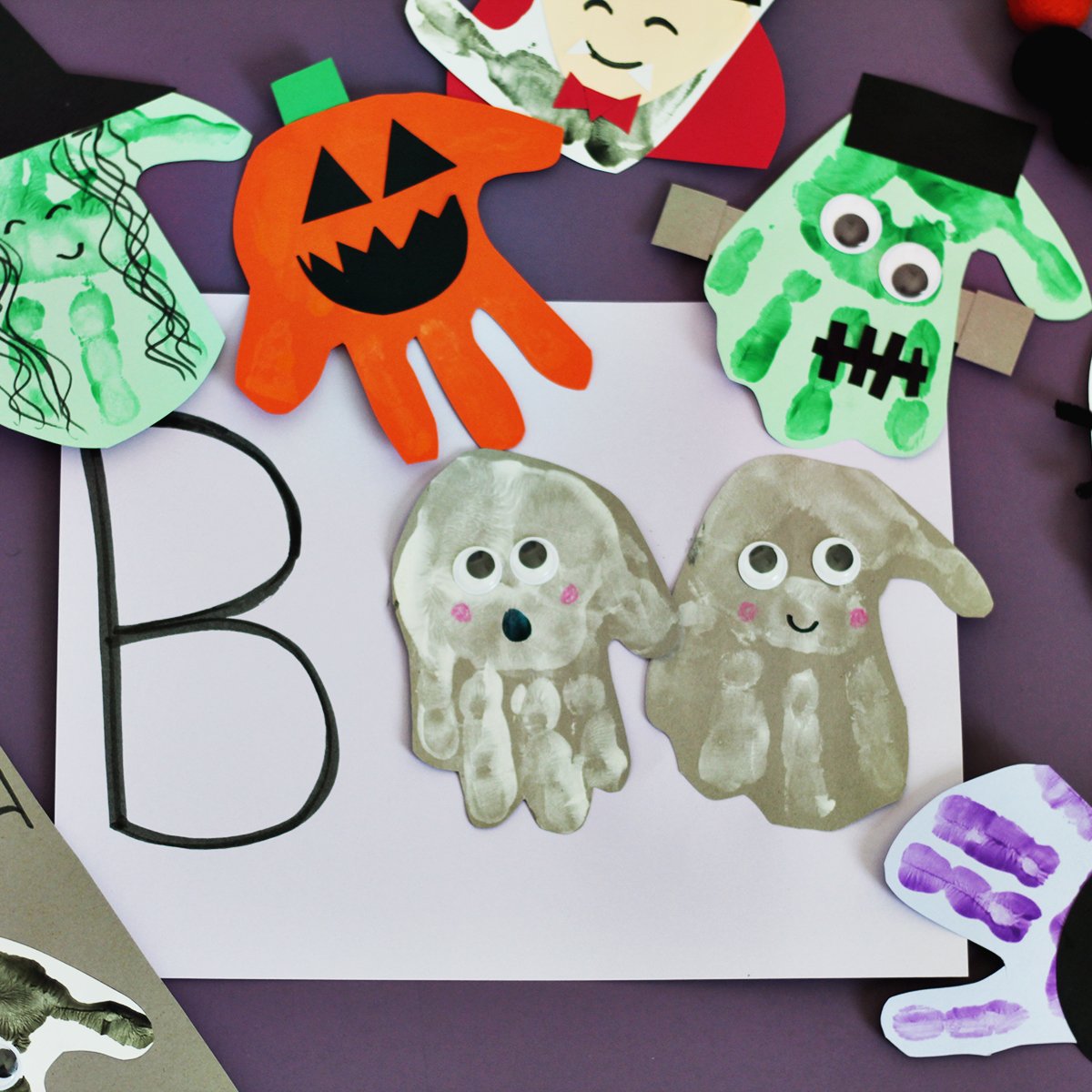 Grey paper with white handprints to make a ghost next to the letter B on a piece of paper.