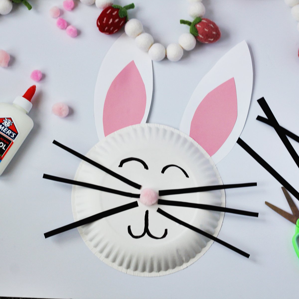 Paper plate with black strips glued on for whiskers and cardstock paper made into bunny ears to make a rabbit face.