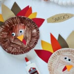 paper plate colored brown with feathers made out of cardstock in red, yellow, orange and brown.