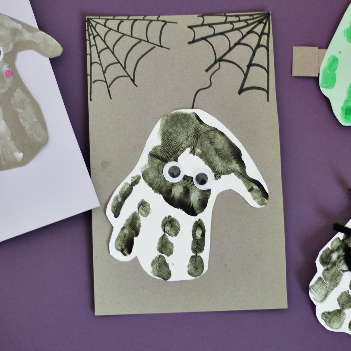 Black painted handprint on white paper on a grey background made to look like a spider.