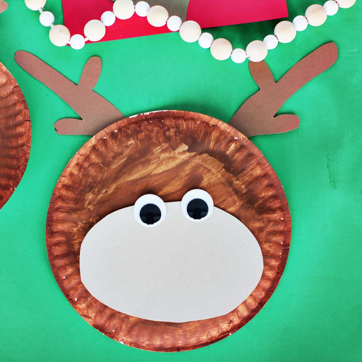 paper plate craft with googley eyes being added to make a reindeer.