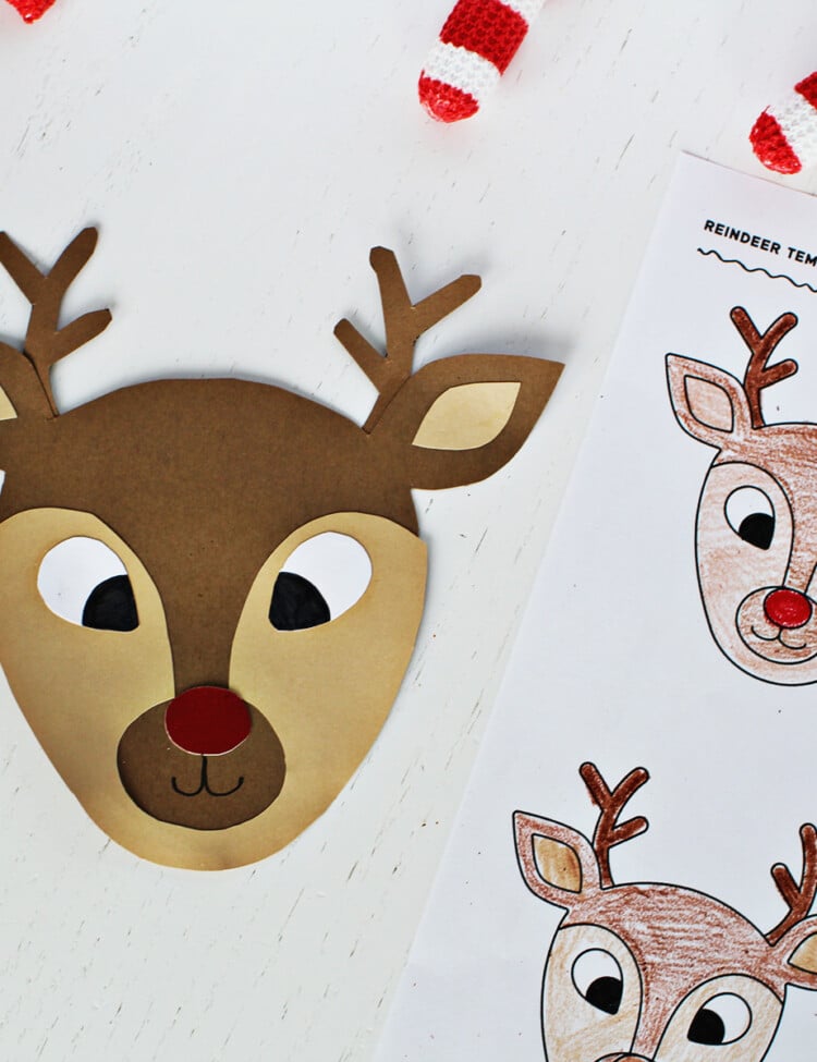 Reindeer face cut out and glued together from cardstock next to a coloring page with reindeer faces on it.